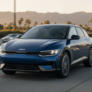 Kia EV4 GT electric sedan driving on a California highway during sunset, showcasing sleek fastback design.