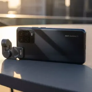 ASUS Zenfone 12 Ultra flagship smartphone placed on a minimal outdoor table, soft golden-hour lighting, premium matte glass back.