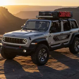 Jeep Recon EV, rugged electric SUV parked on a rocky terrain at sunrise, open-air design with removable doors, signature Jeep grille with futuristic LED lighting